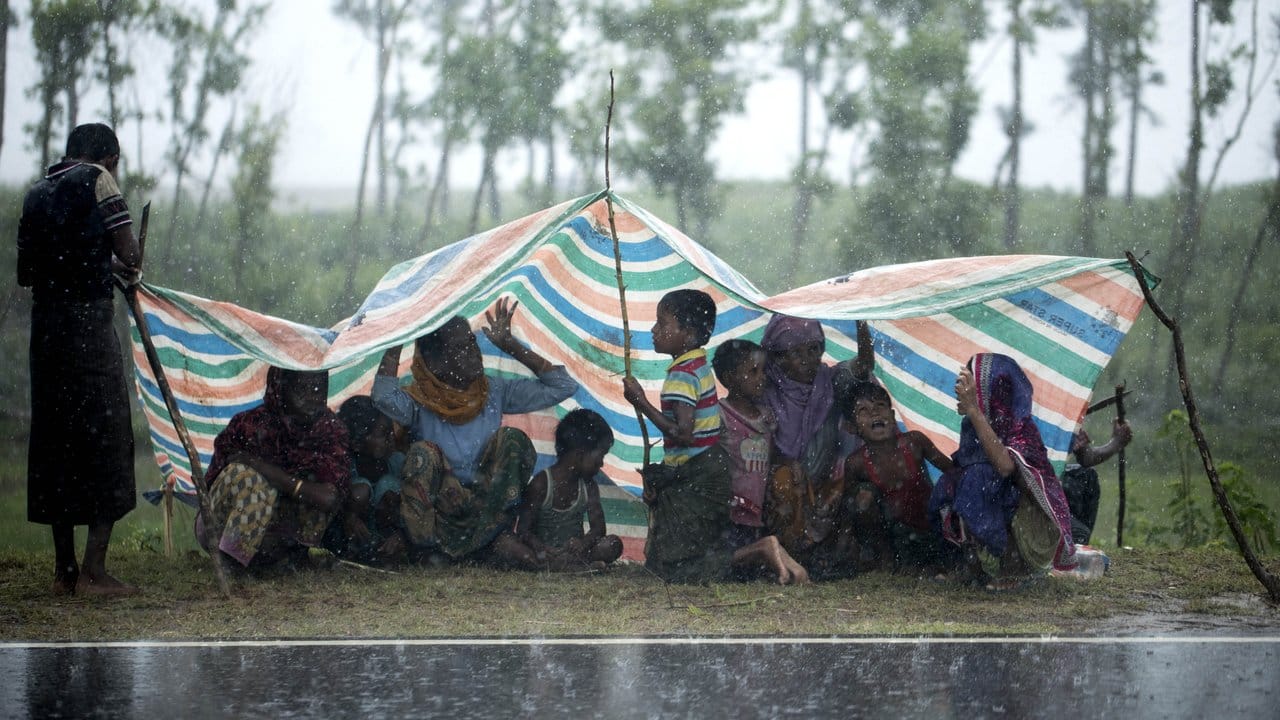 Rohingya-Flüchtlinge aus Myanmar sitzen in der Stadt Cox’s Bazar in Bangladesch unter einer Plastikplane, um sich vor Regen zu schützen. Rohingya-Flüchtlinge aus Myanmar sitzen in der Stadt Cox’s Bazar in Bangladesch unter einer Plastikplane, um sich vor Regen zu schützen.