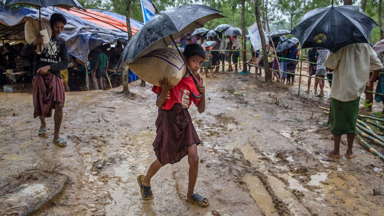 Ein Junge der Rohingyas trägt in einem Flüchtlingslager nahe Cox's Bazar einen von Hilfsorganisationen gespendeten Sack Reis auf seinen Schultern. Ein Junge der Rohingyas trägt in einem Flüchtlingslager nahe Cox's Bazar einen von Hilfsorganisationen gespendeten Sack Reis auf seinen Schultern.