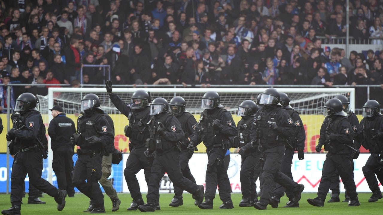 Polizisten vertreiben etwa 25 Kieler Chaoten, die den Platz vor Spielbeginn gestürmt hatten.