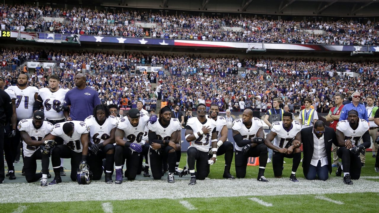 Spieler des Football-Teams Baltimore Ravens knien in London während der US-Nationalhymne aus Protest auf dem Rasen.