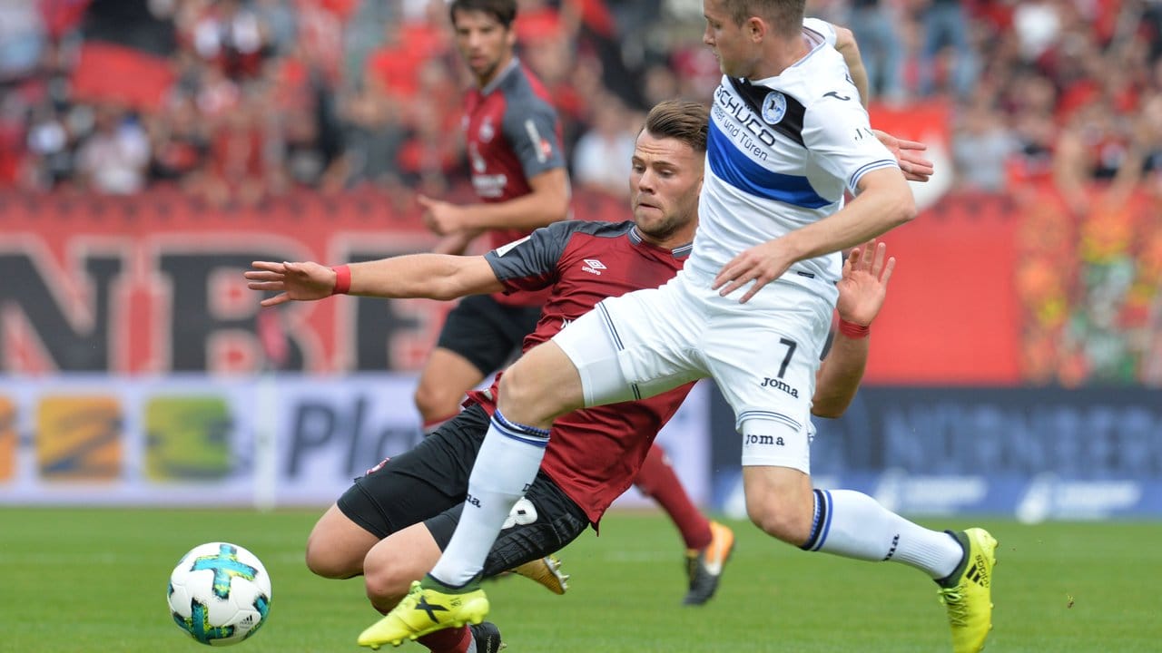Der Nürnberger Eduard Löwen (l) kommt beim Kampf um den Ball gegen den Bielefelder Patrick Weihrauch zu Fall. Der Nürnberger Eduard Löwen (l) kommt beim Kampf um den Ball gegen den Bielefelder Patrick Weihrauch zu Fall.