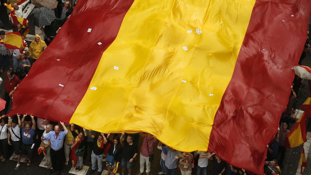 Demonstranten tragen in Barcelona bei einer Demonstration gegen die Unabhängigkeit Kataloniens eine riesige spanische Flagge. Demonstranten tragen in Barcelona bei einer Demonstration gegen die Unabhängigkeit Kataloniens eine riesige spanische Flagge.