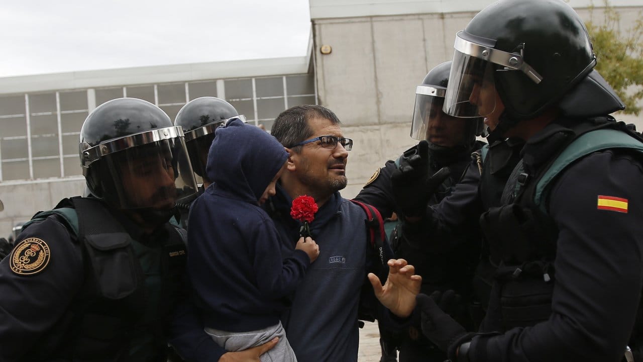 Einheiten der Guardia Civil zwingen einen Mann mit Kind am Eingang eines Wahllokals umzukehren. Einheiten der Guardia Civil zwingen einen Mann mit Kind am Eingang eines Wahllokals umzukehren.