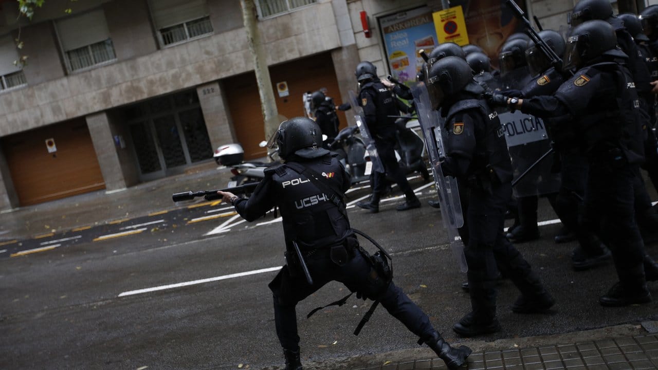 Ein spanischer Polizist schießt mit Gummigeschossen auf Menschen, die in Barcelona zu einem Wahllokal wollen. Ein spanischer Polizist schießt mit Gummigeschossen auf Menschen, die in Barcelona zu einem Wahllokal wollen.