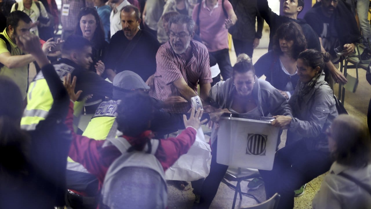 Spanische Polizisten versuchen in einem Wahllokal Wahlhelfern eine Urne zu entreißen. Spanische Polizisten versuchen in einem Wahllokal Wahlhelfern eine Urne zu entreißen.