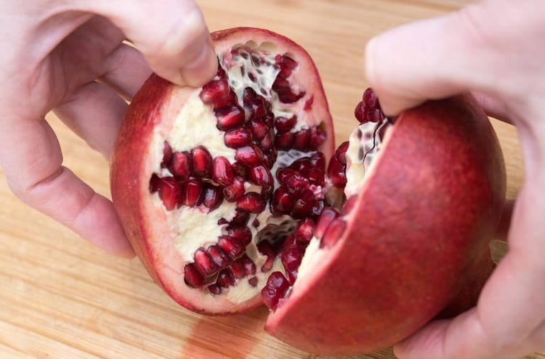 Den Granatapfel vorsichtig an der eingeschnittenen Stelle auseinanderdrücken.