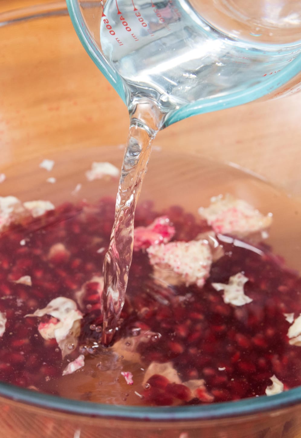 Die Granatapfelkerne in der Schüssel mit Wasser auffüllen.