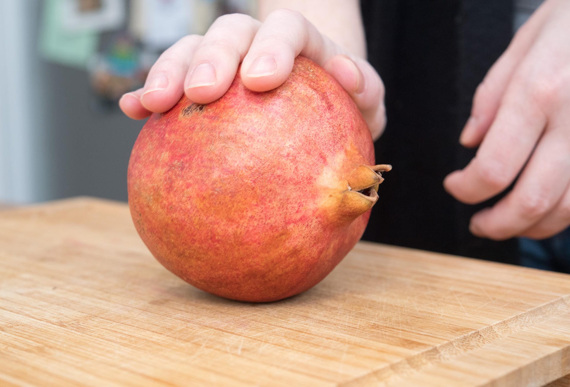 Den Granatapfel auf ein Küchenbrett legen und mit der Handfläche hin- und herrollen, dabei die Schale leicht eindrücken.