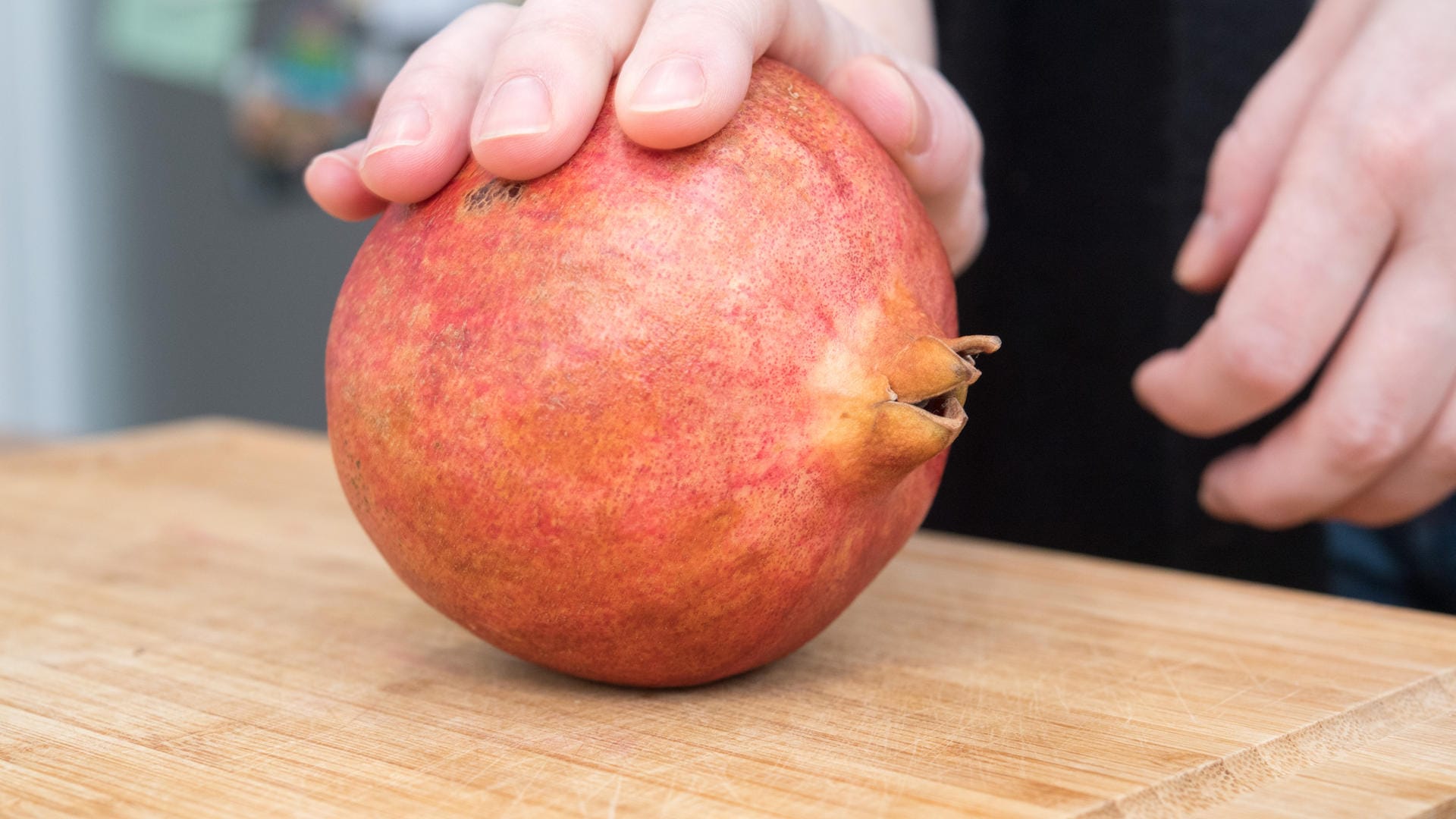 Den Granatapfel auf ein Küchenbrett legen und mit der Handfläche hin- und herrollen, dabei die Schale leicht eindrücken.