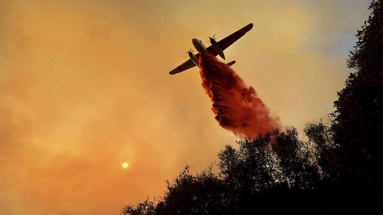 Ein Löschflugzeug lässt in Geyserville Löschmittel über einem Waldbrand ab.