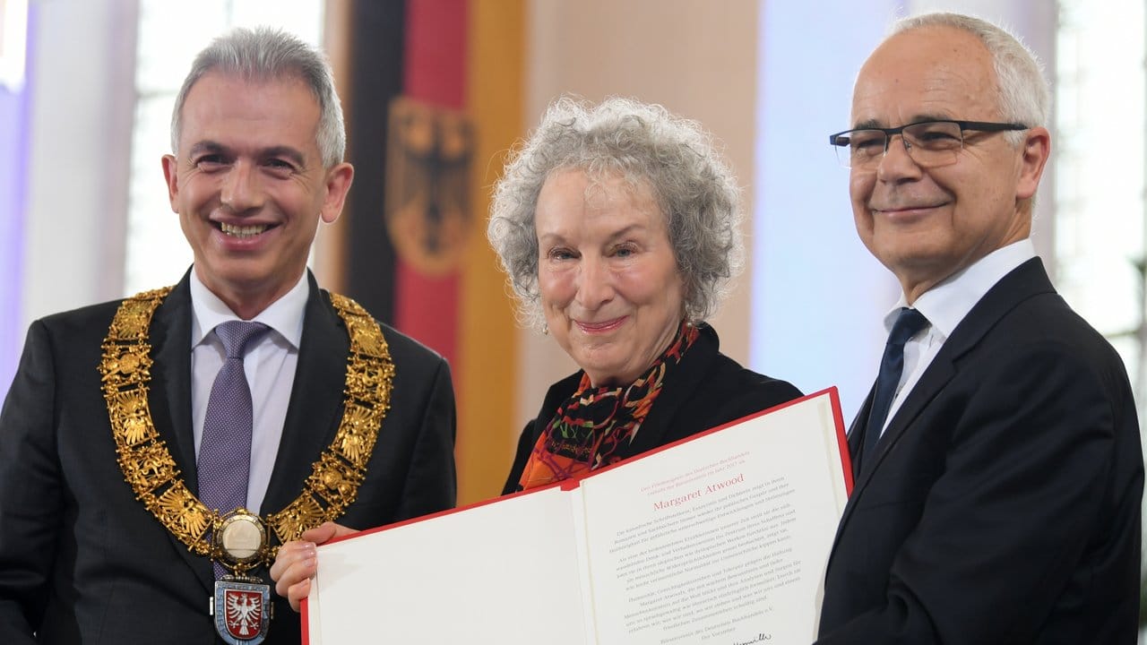Margaret Atwood wird im Beisein von Frankfurts Oberbürgermeister Peter Feldmann (l) von Heinrich Riethmüller, Vorsteher des Börsenvereins des Deutschen Buchhandels, ausgezeichnet.