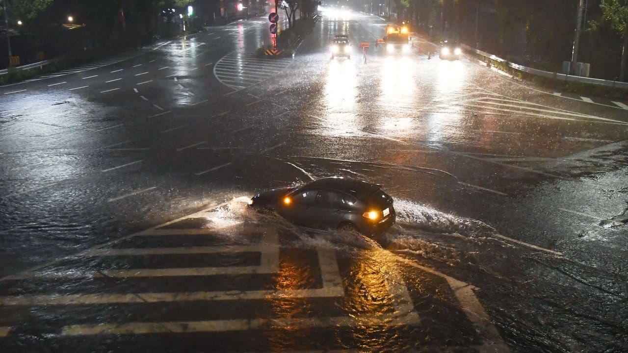 Ein Auto kämpft sich in Nagoya durch eine vom Taifun überflutete Straße.