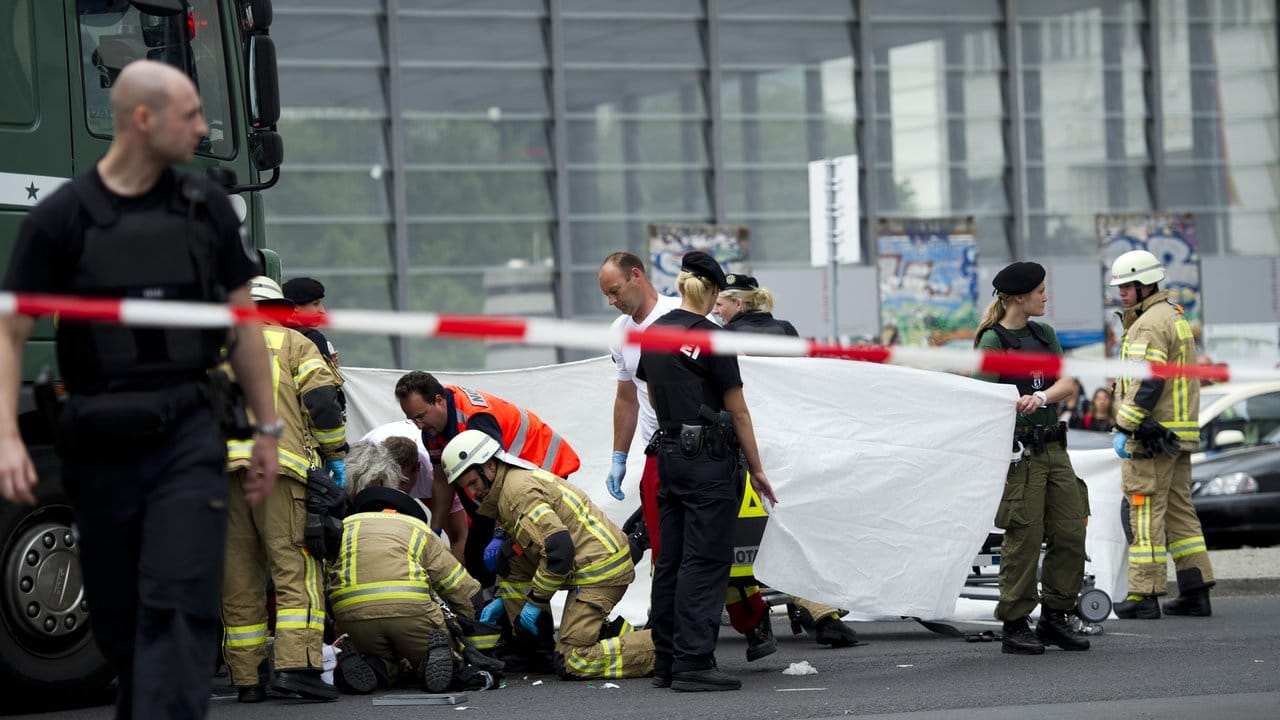 Rettungskräfte helfen auf der Straßenkreuzung am Potsdamer Platz in Berlin einem verletzten Radfahrer, der unter einem Lastwagen liegt. Rettungskräfte helfen auf der Straßenkreuzung am Potsdamer Platz in Berlin einem verletzten Radfahrer, der unter einem Lastwagen liegt.