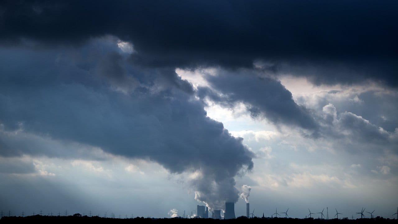 Wolken ziehen bei Köln-Worringen über ein Braunkohlekraftwerk.
