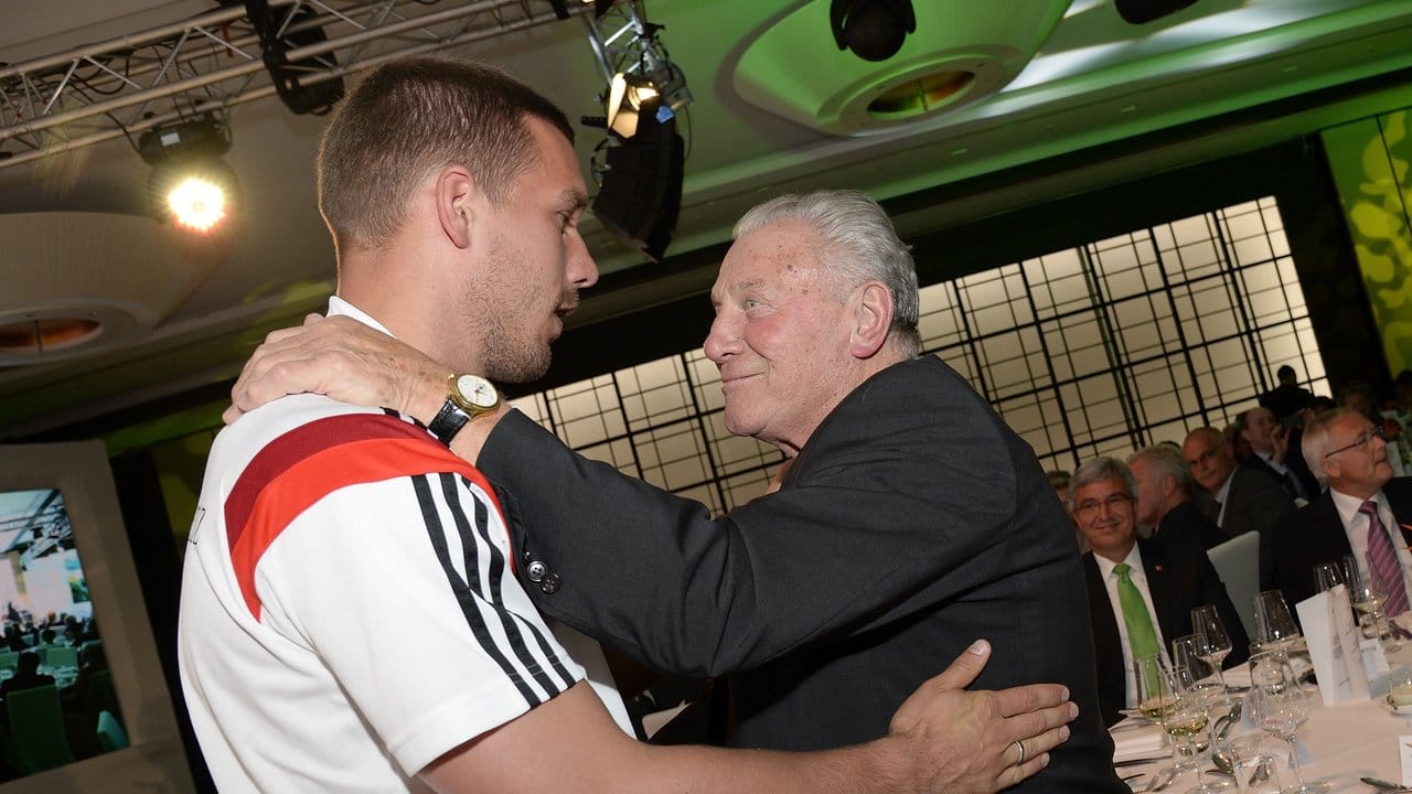 Lukas Podolski (l) umarmt Hans Schäfer (r) 2014 während einer WM-Party des Deutschen Fußball-Bundes in Düsseldorf.