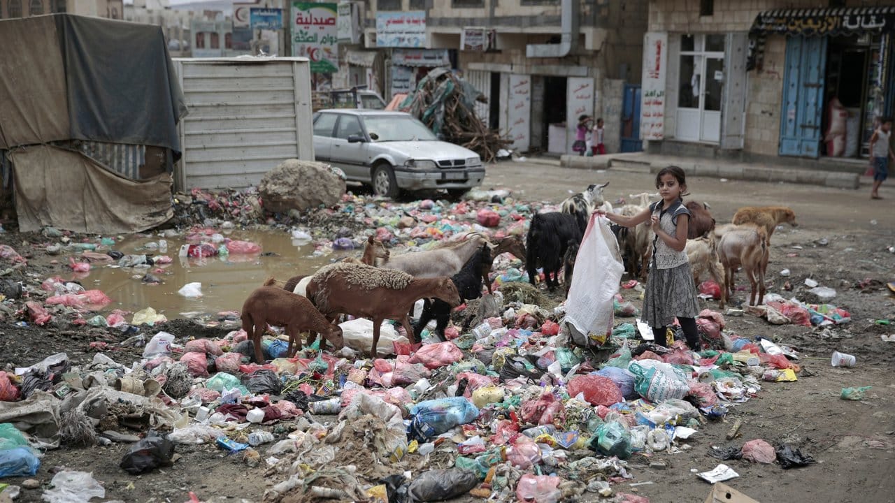 Ein Mädchen sucht im Abfall auf einer Straße in Sanaa nach verwertbarem.