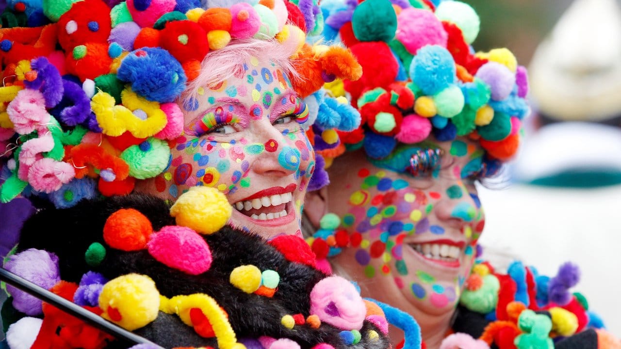 Zwei bunt geschmückte Karnevalistinnen feiern Hoppeditz erwachen.
