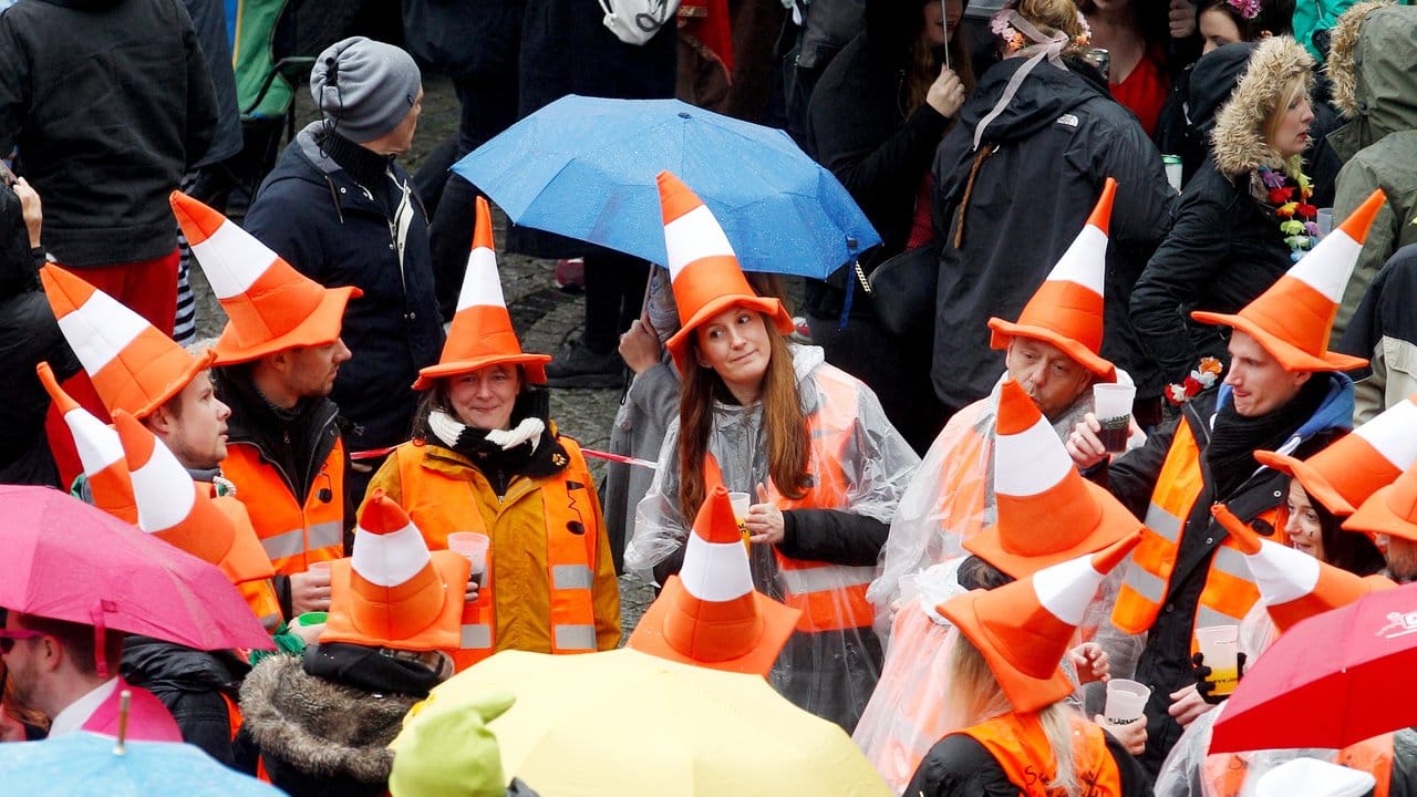Mit Baustellenhütchen verkleidete Karnevalisten feiern trotz des schlechten Wetters.