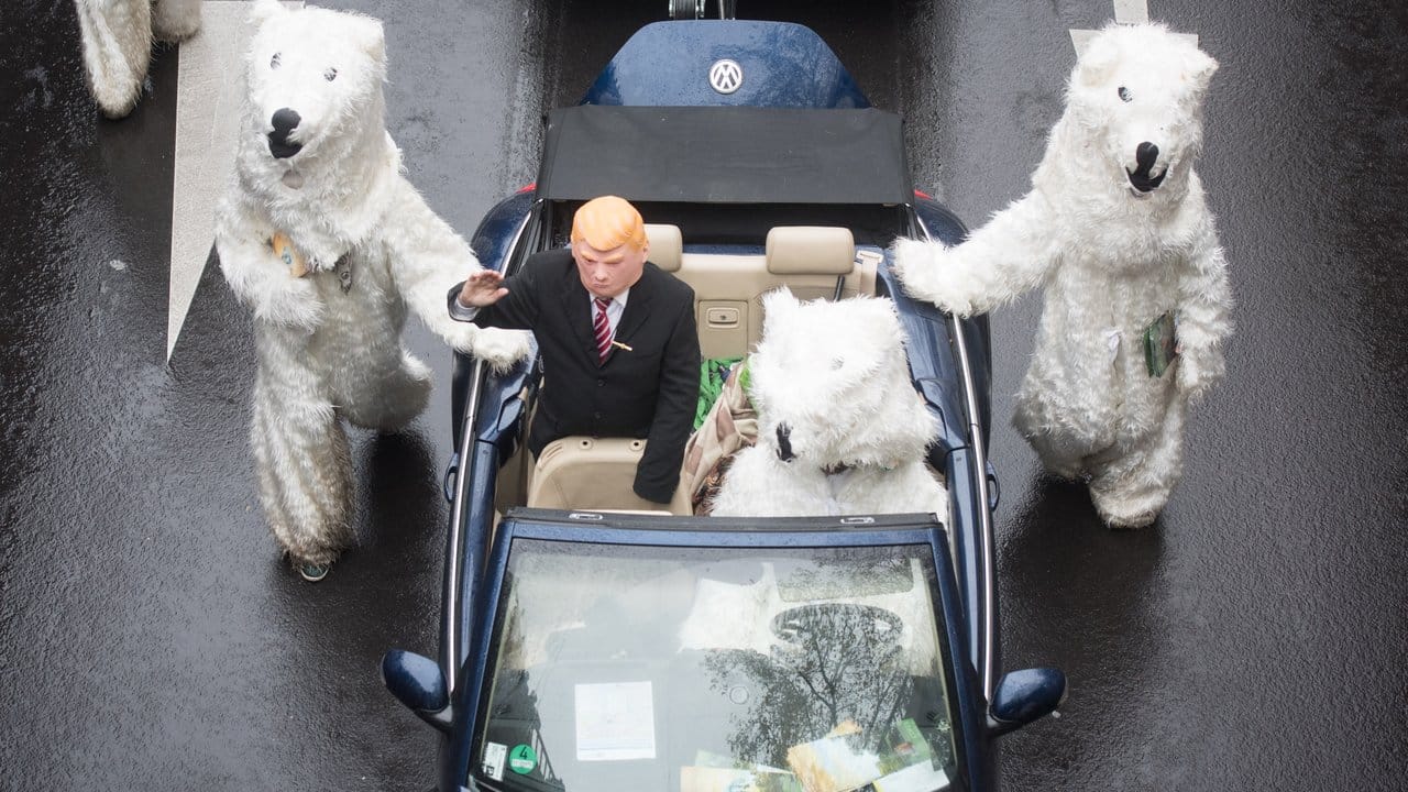 Ein als US-Präsident Donald Trump verkleideter Teilnehmer einer Kundgebungen des Bündnisses "No Climate Change" winkt in Bonn aus einem von einem "Eisbären" gesteuerten Cabrio.