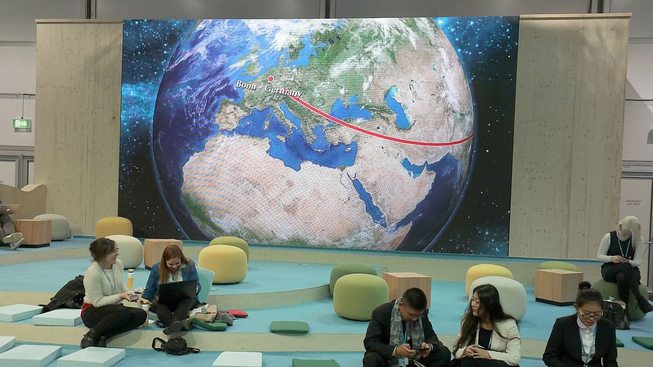 Teilnehmer der Weltklimakonferenz in Bonn sitzen vor der Darstellung einer Weltkugel.