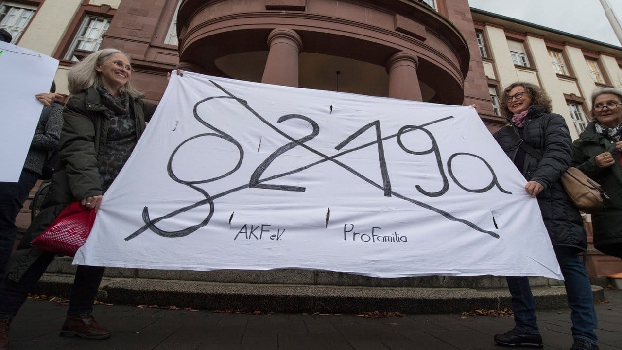 Mit einem Transparent fordern Demonstrantinnen die Abschaffung des Paragrafen 219a.