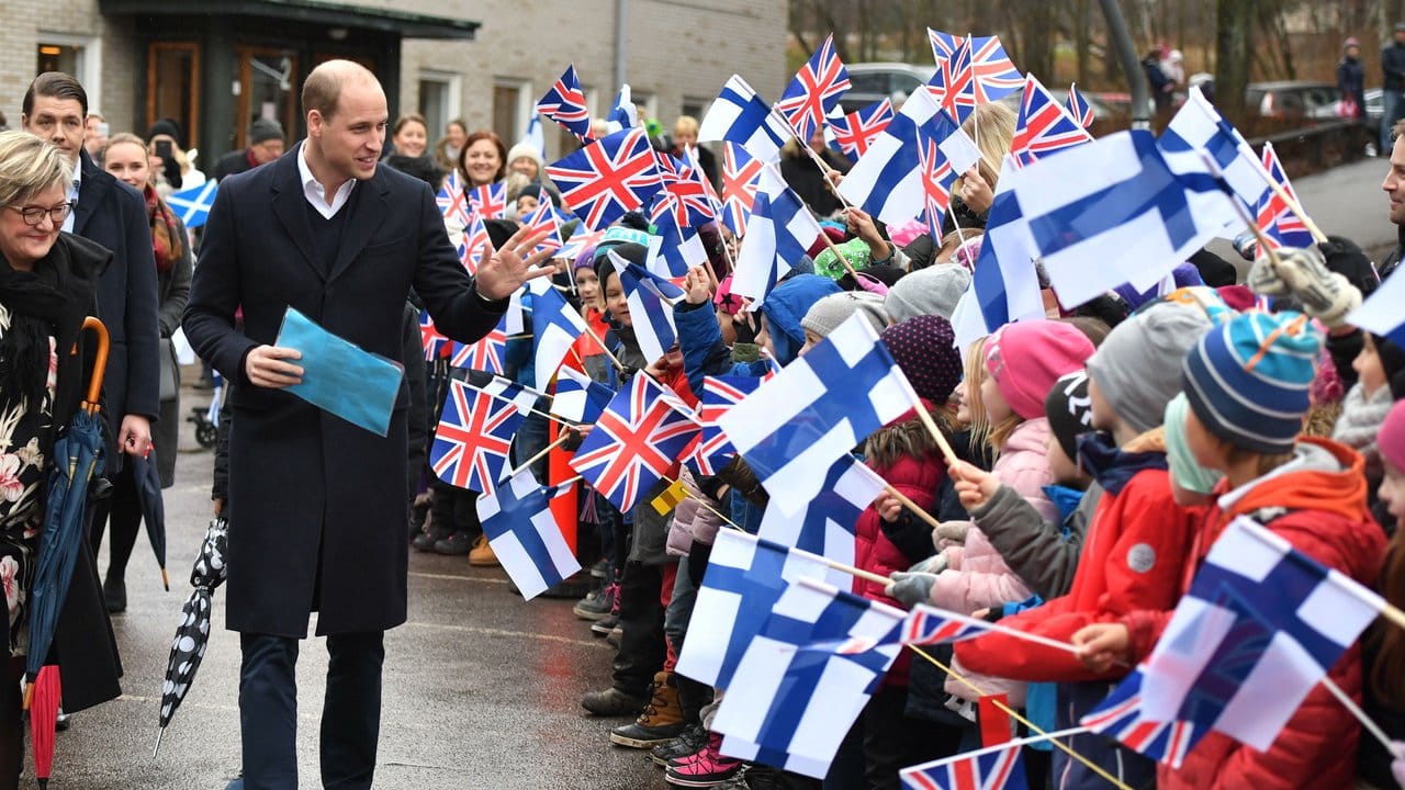Der britische Prinz William wird von Schulkindern in Helsinki mit Fähnchen begrüßt.