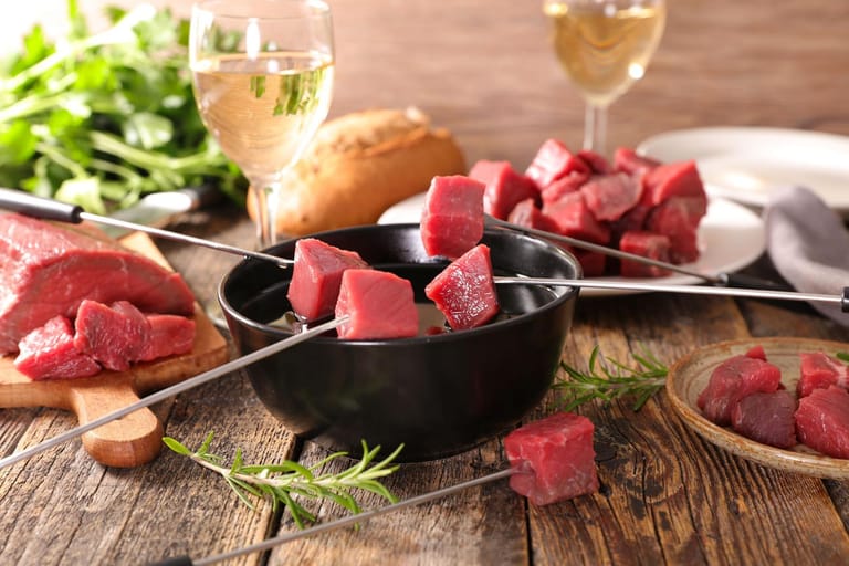 Für ein klassisches Rezept Fleischfondue à la bourgignon, das aus dem französischen Burgund stammt, schneidet man ein Rumpsteak in gulaschgroße Würfel und gart das Fleisch in heißem Fett.