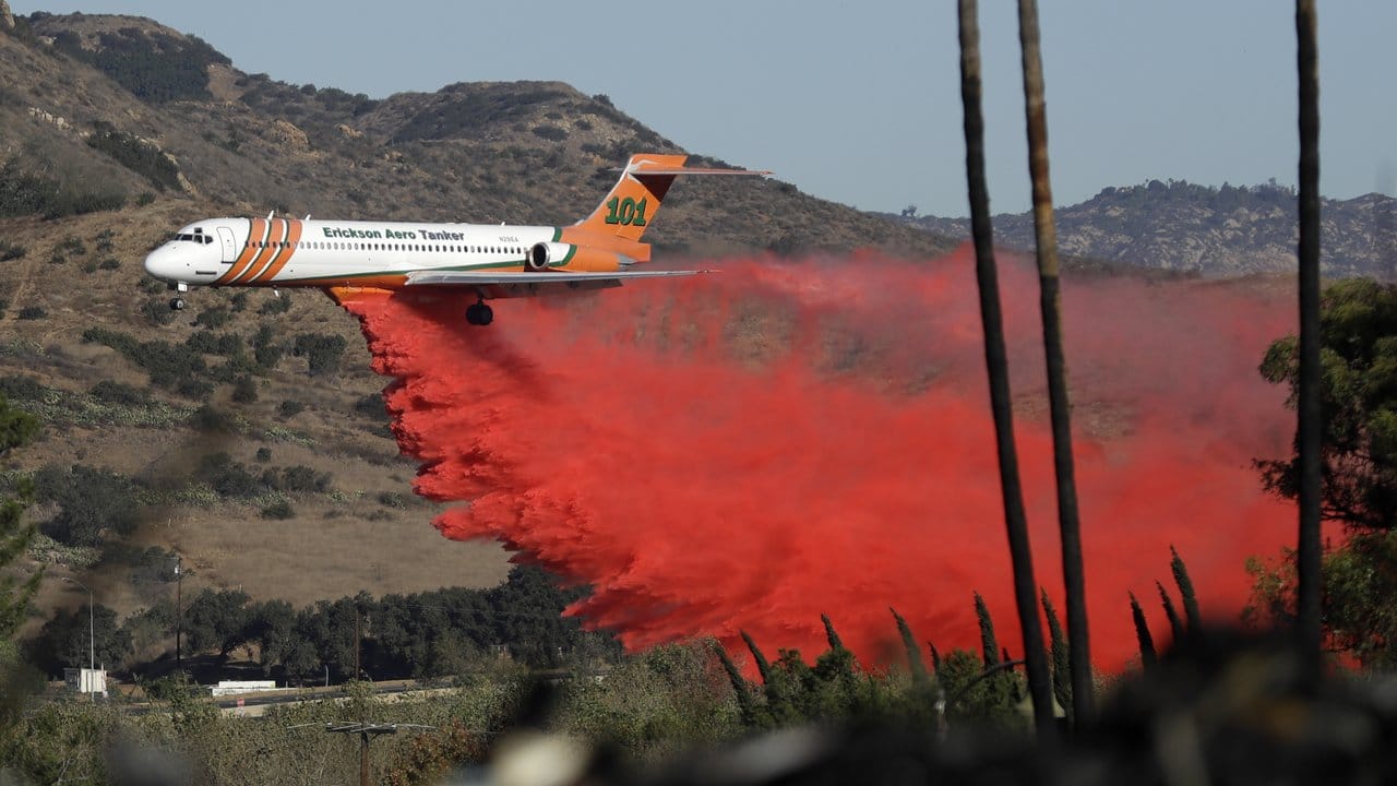 Ein Löschflugzeug wirft seine rot gefärbte Wasserladung ab. Ein Löschflugzeug wirft seine rot gefärbte Wasserladung ab.