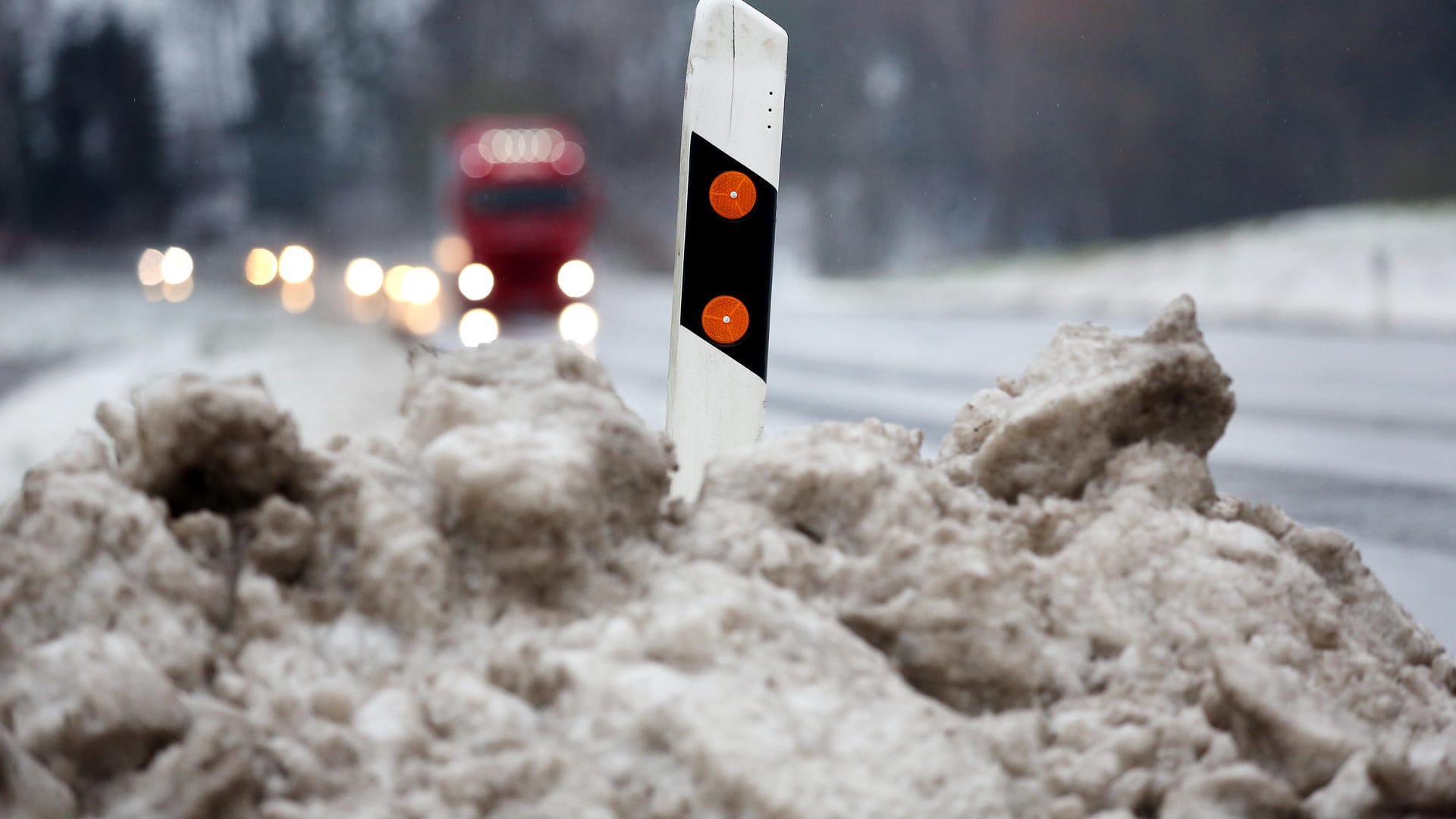 Ein Leitpfosten steht an der B 312 bei Hailtingen (Baden-Württemberg) im vom Tauwasser gefärbten Schnee.