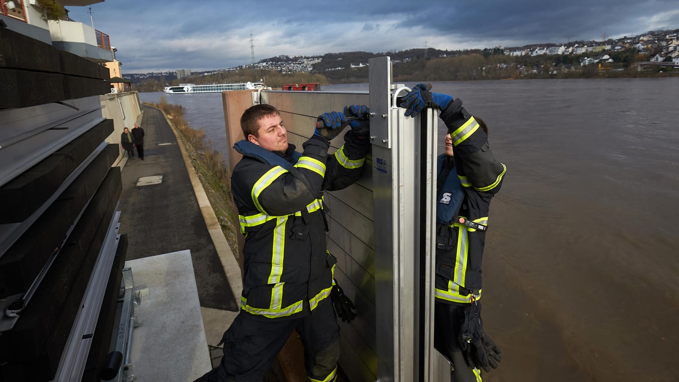Steigende Pegel am Rheinufer in Koblenz: Feuerwehrleute bauen eine mobile Hochwasserschutzmauer auf.