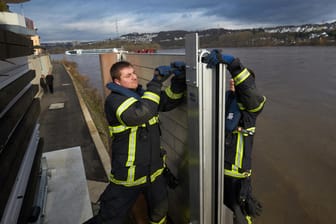Steigende Pegel am Rheinufer in Koblenz: Feuerwehrleute bauen eine mobile Hochwasserschutzmauer auf.