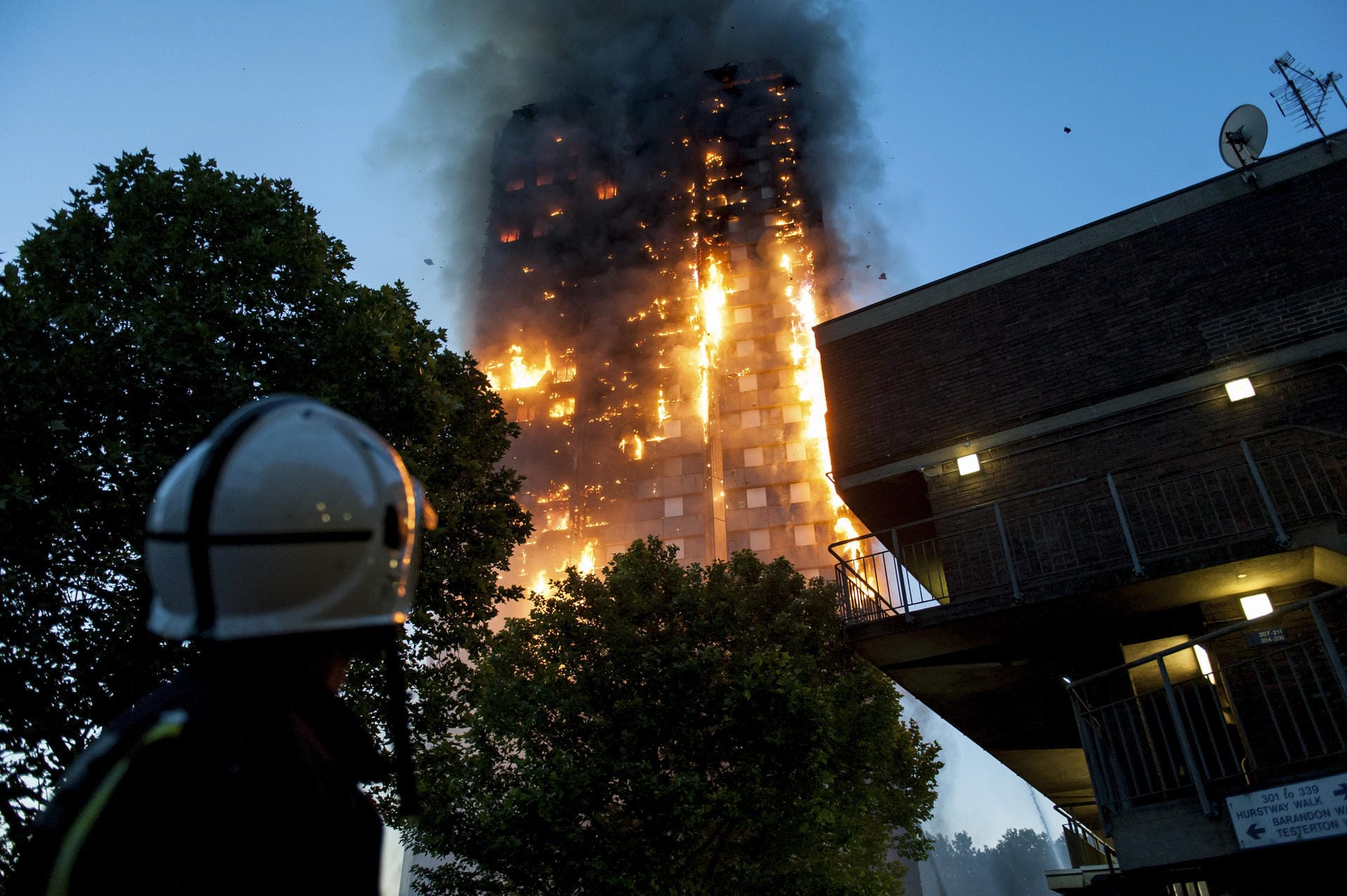 Feuerwehrleute beobachten hilflos, wie der Grenfell Tower in London abbrennt. Der Hochhausbrand steht beispielhaft für die Folgen von Sparwut und mangelhafte gesetzliche Vorschriften.