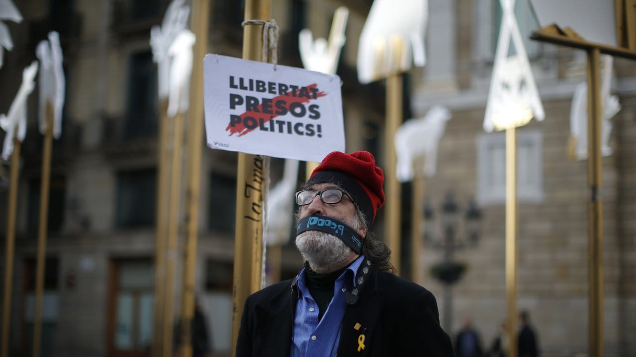 Ein Mann mit einer Binde vor dem Mund fordert in Barcelona "Freiheit für politische Gefangene" und meint damit die inhaftierten katalanischen Politiker.