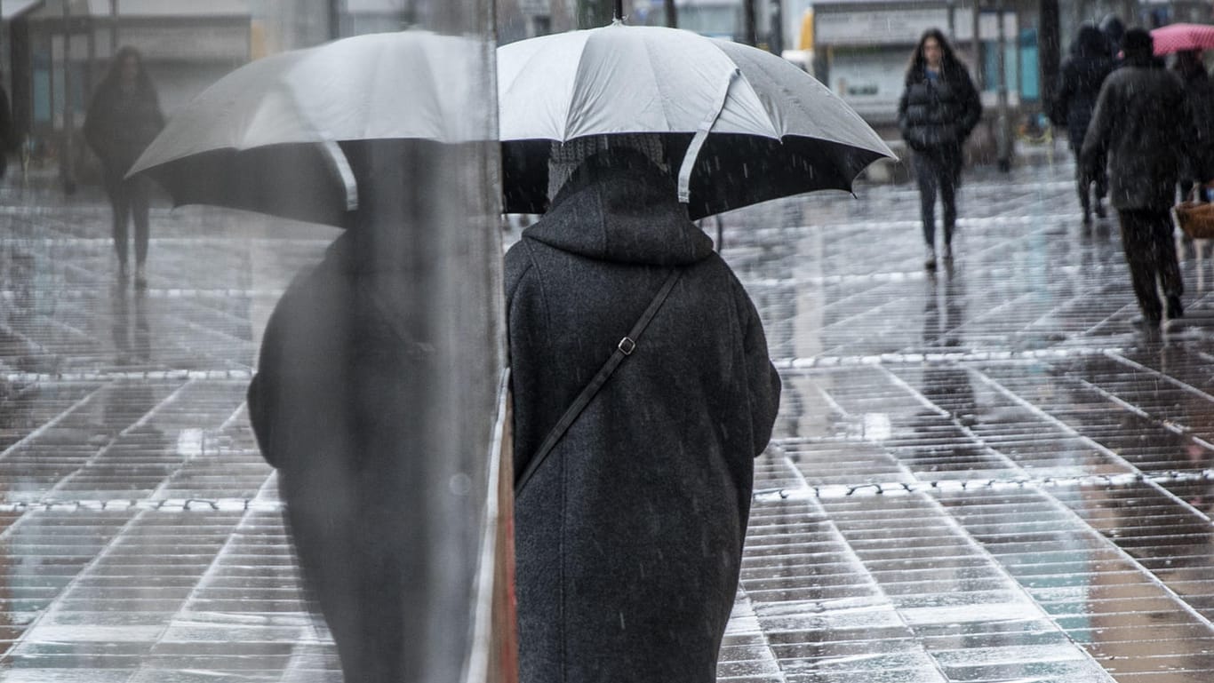 Fußgängerin mit Regenschirm in Frankfurt: An Silvester soll das Wetter in einigen Regionen Deutschlands ungemütlich werden.