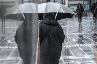 Fußgängerin mit Regenschirm in Frankfurt: An Silvester soll das Wetter in einigen Regionen Deutschlands ungemütlich werden.