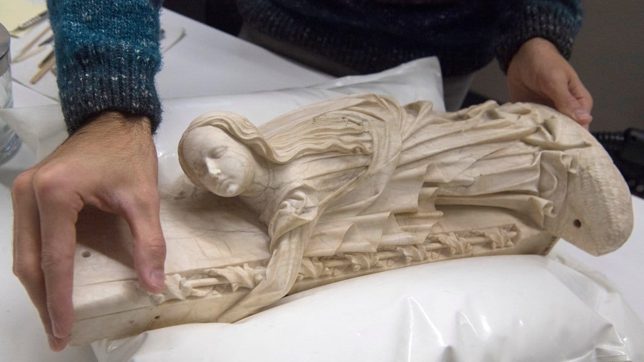 Auf einem weichen Spezialkissen schiebt ein Restaurator die Maria-Figur des Rimini-Altars in Position.