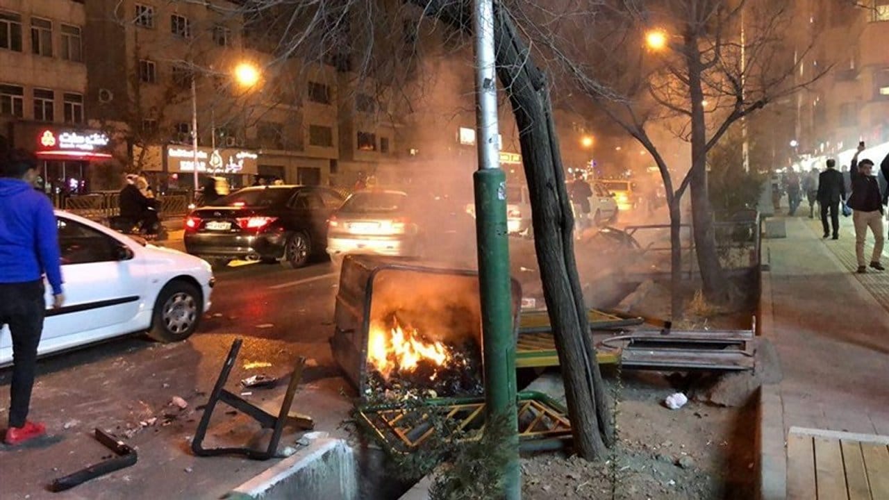 Eine brennende Mülltonne liegt nach Protesten am Straßenrand.