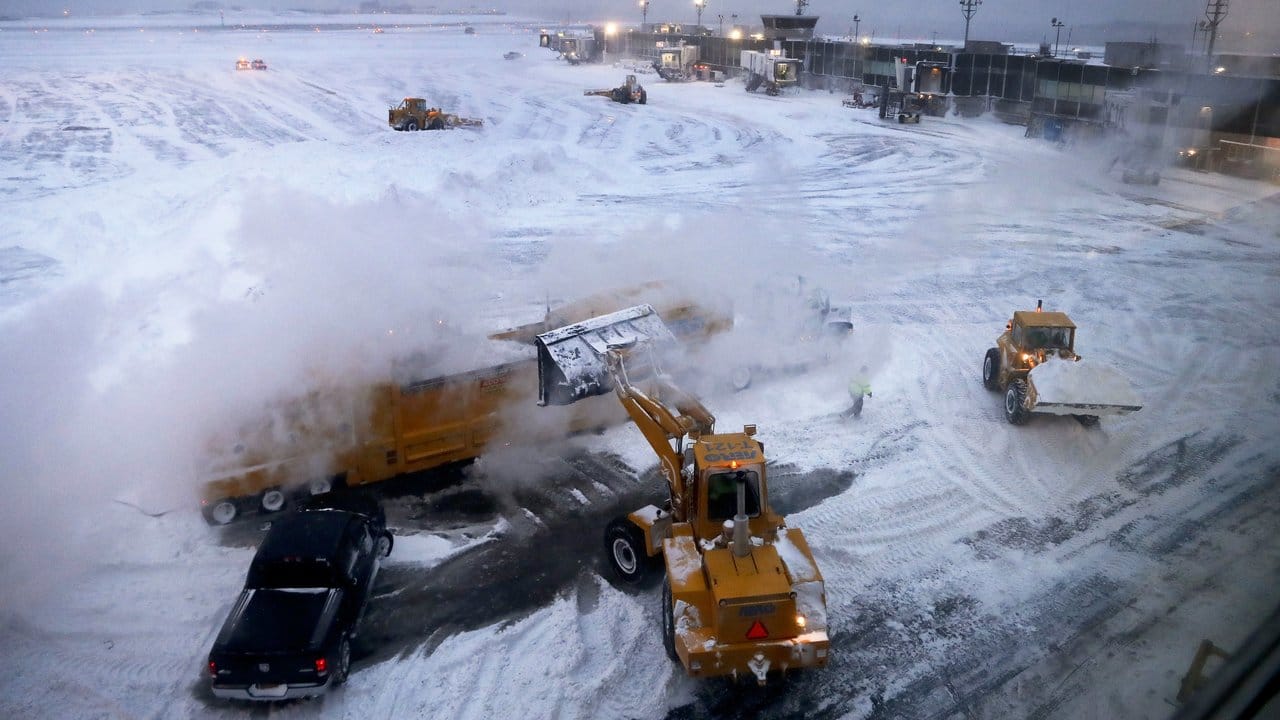 Frontlader schaufeln auf dem LaGuardia Airport in New York Schnee in einen Schneeschmelzer. Frontlader schaufeln auf dem LaGuardia Airport in New York Schnee in einen Schneeschmelzer.