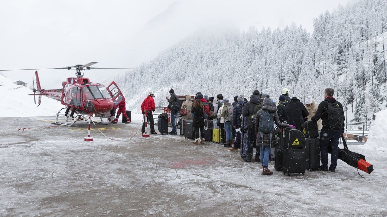 Touristen warten auf dem Hubschrauberlandeplatz der Air Zermatt auf ihren Flug ins Tal.