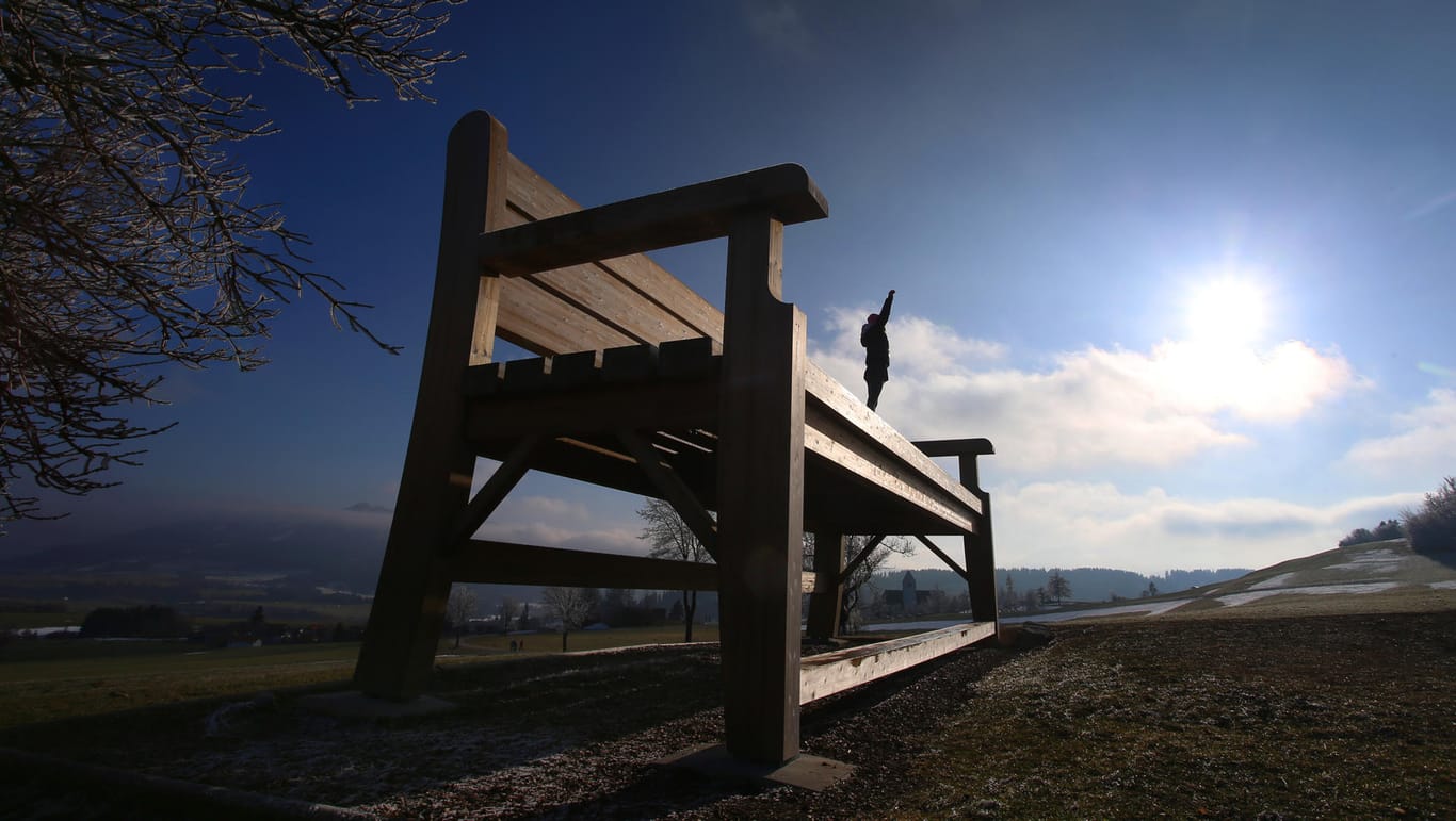 Eine Frau begrüßt die Sonne auf der sechs Meter hohen "Wanderbank Allgäu" im bayerischen Oy-Mittelberg: Am Mittwoch steigen die Temperaturen fast überall in Deutschland auf bis zu 15 Grad.