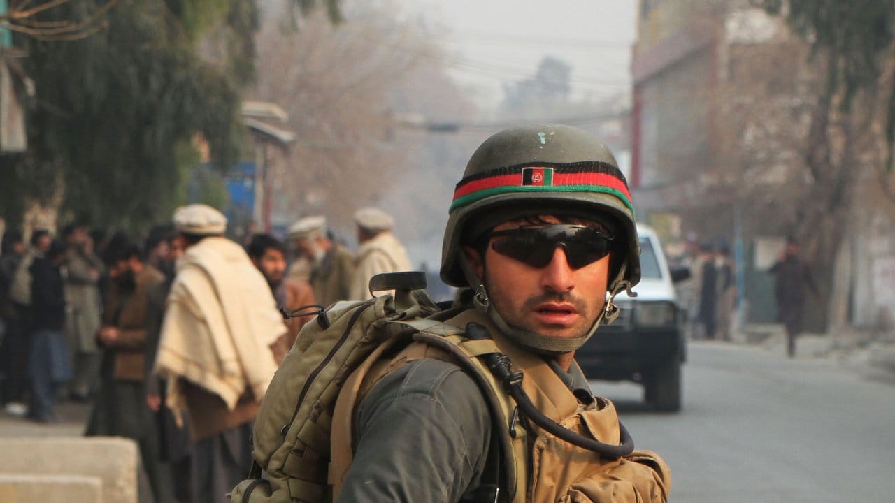 Nach einem Überfall steht ein Mitglied der afghanischen Sicherheitskräfte am Ort des Anschlags.