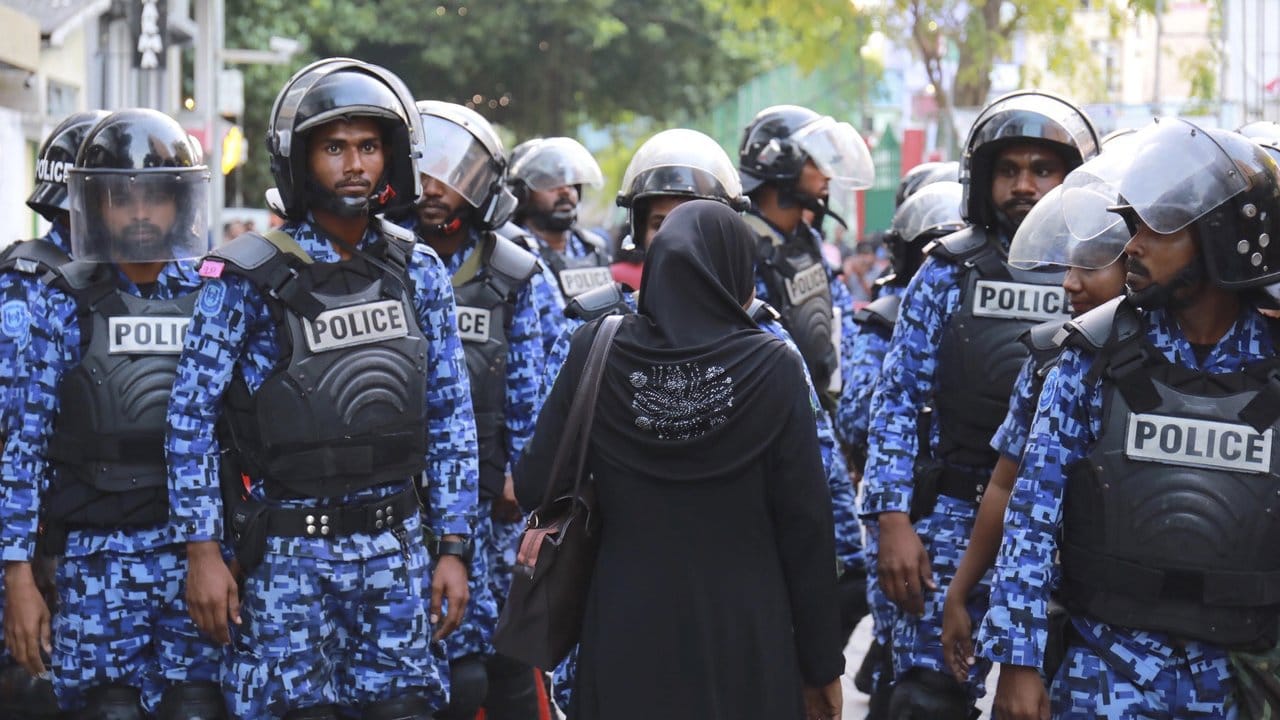 Eine Unterstützerin der Opposition steht bei einer Demonstration in Malé Polizisten gegenüber.