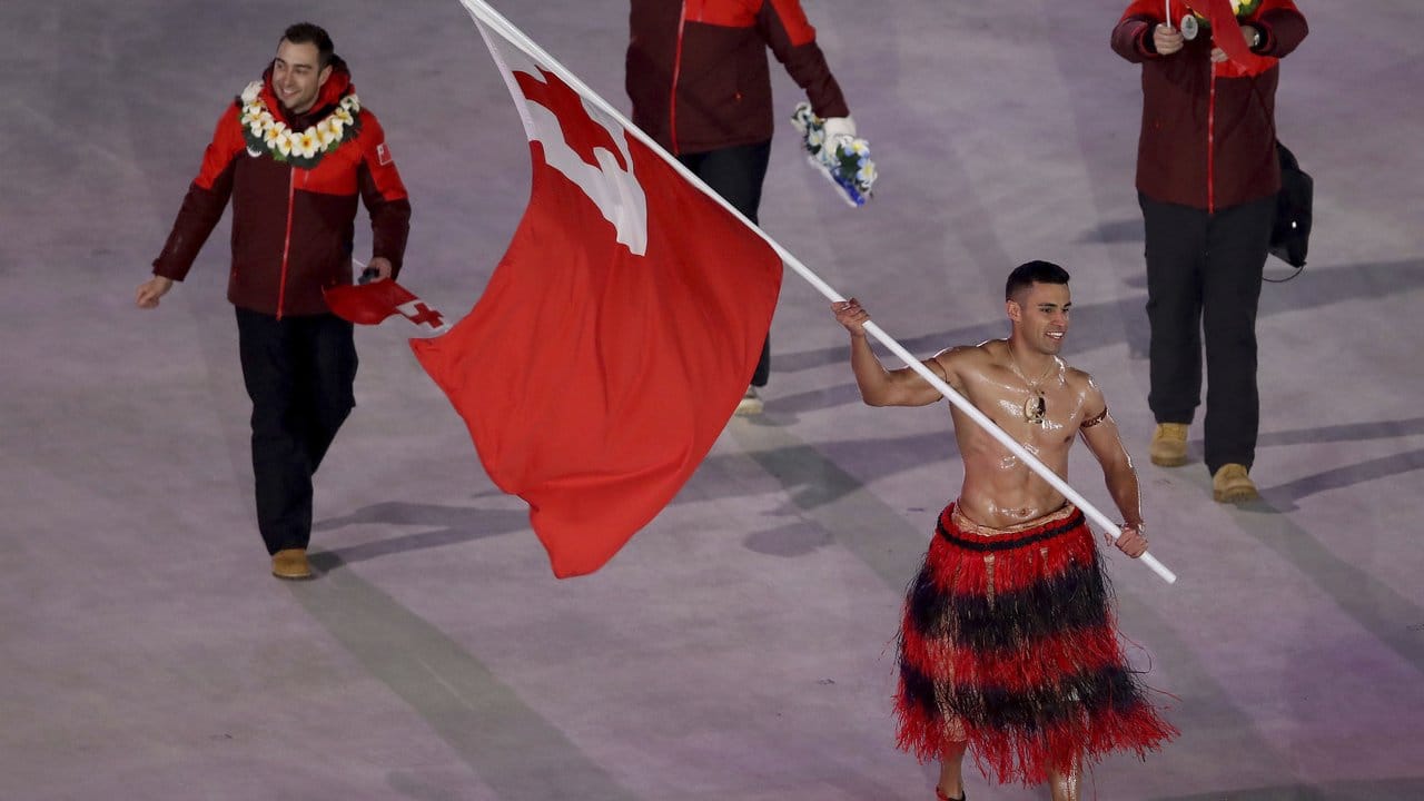 Skilangläufer Pita Taufatofua aus Tonga trägt die Flagge seines Landes mit bloßem Oberkörper. Skilangläufer Pita Taufatofua aus Tonga trägt die Flagge seines Landes mit bloßem Oberkörper.