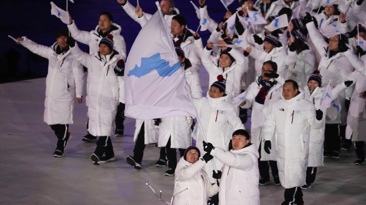 Die gemeinsame Olympia-Mannschaft von Süd- und Nordkorea wird von den zwei Fahnenträgern ins Olympiastadion geführt. Die gemeinsame Olympia-Mannschaft von Süd- und Nordkorea wird von den zwei Fahnenträgern ins Olympiastadion geführt.