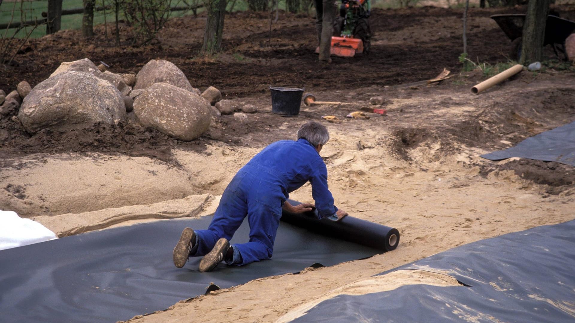 Anlegen eines Folien-Gartenteiches: Dann wird die Teichfolie ausgerollt.