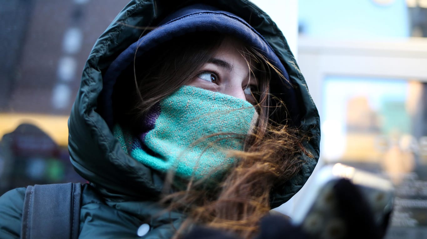 Eine Frau schützt sich mit Schal und Kapuze gegen Kälte: Am Wochenende droht strenger Frost.