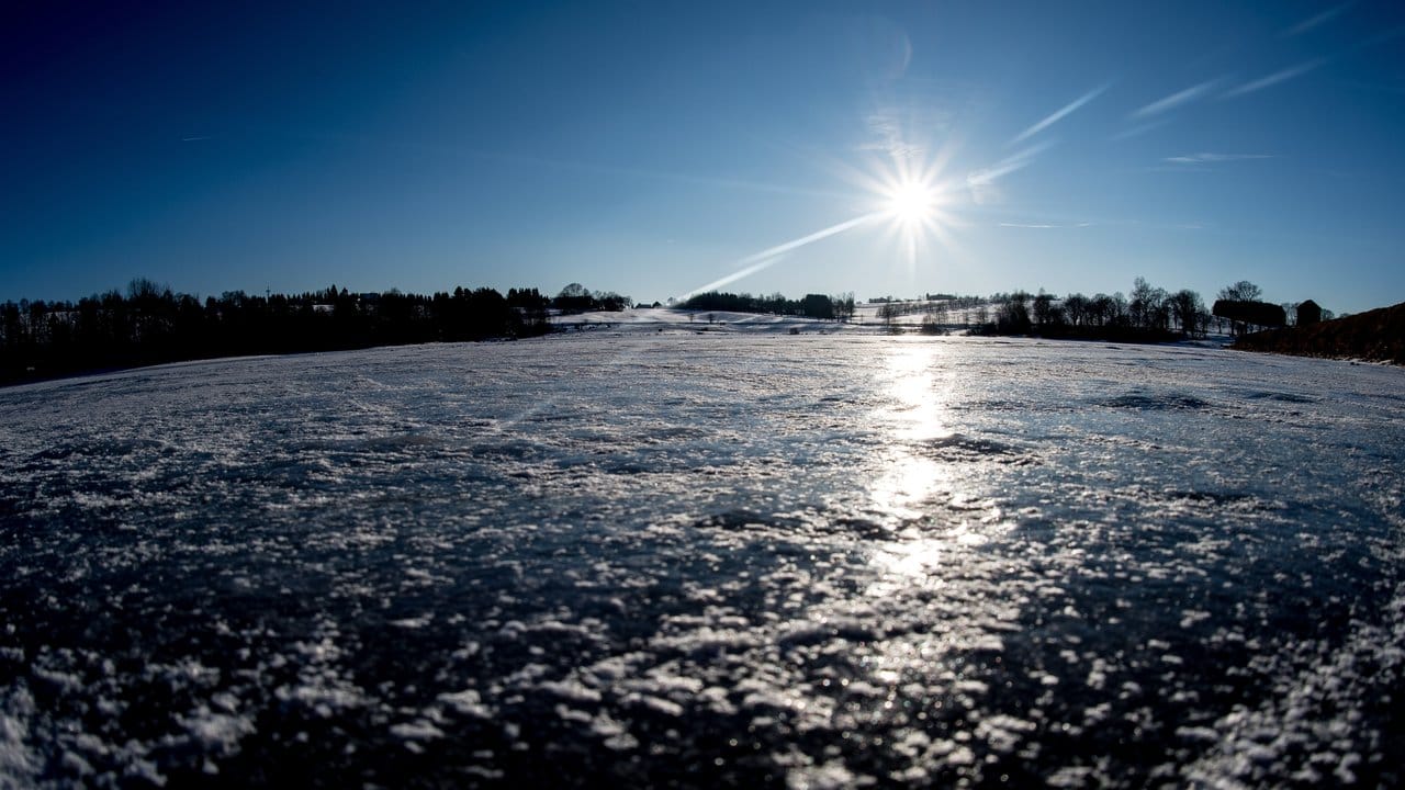 Die Sonne scheint über einem mit Eis bedeckten Teich im Harz in Niedersachsen.