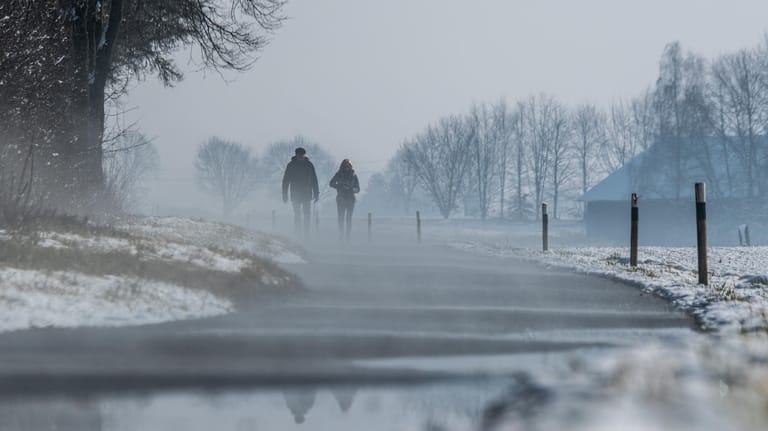 Spaziergänger auf einer Straße in Bayern: In dem Bundesland können die Temperaturen besonders tief fallen.