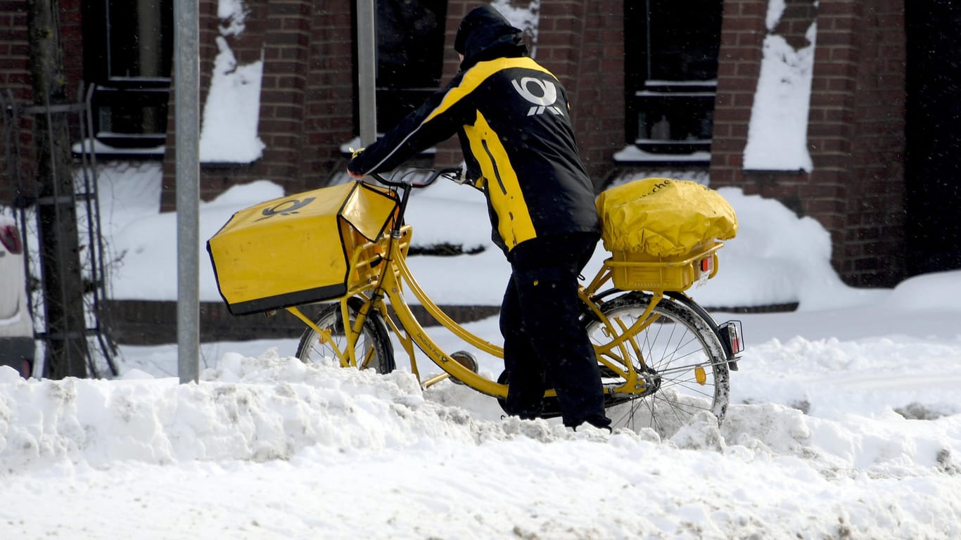 Schleswig-Holstein, Lübeck: Ein Briefträger schiebt sein Rad durch den Schnee: Die nächsten Tage soll es zumindest keine weiteren Schneefälle geben.