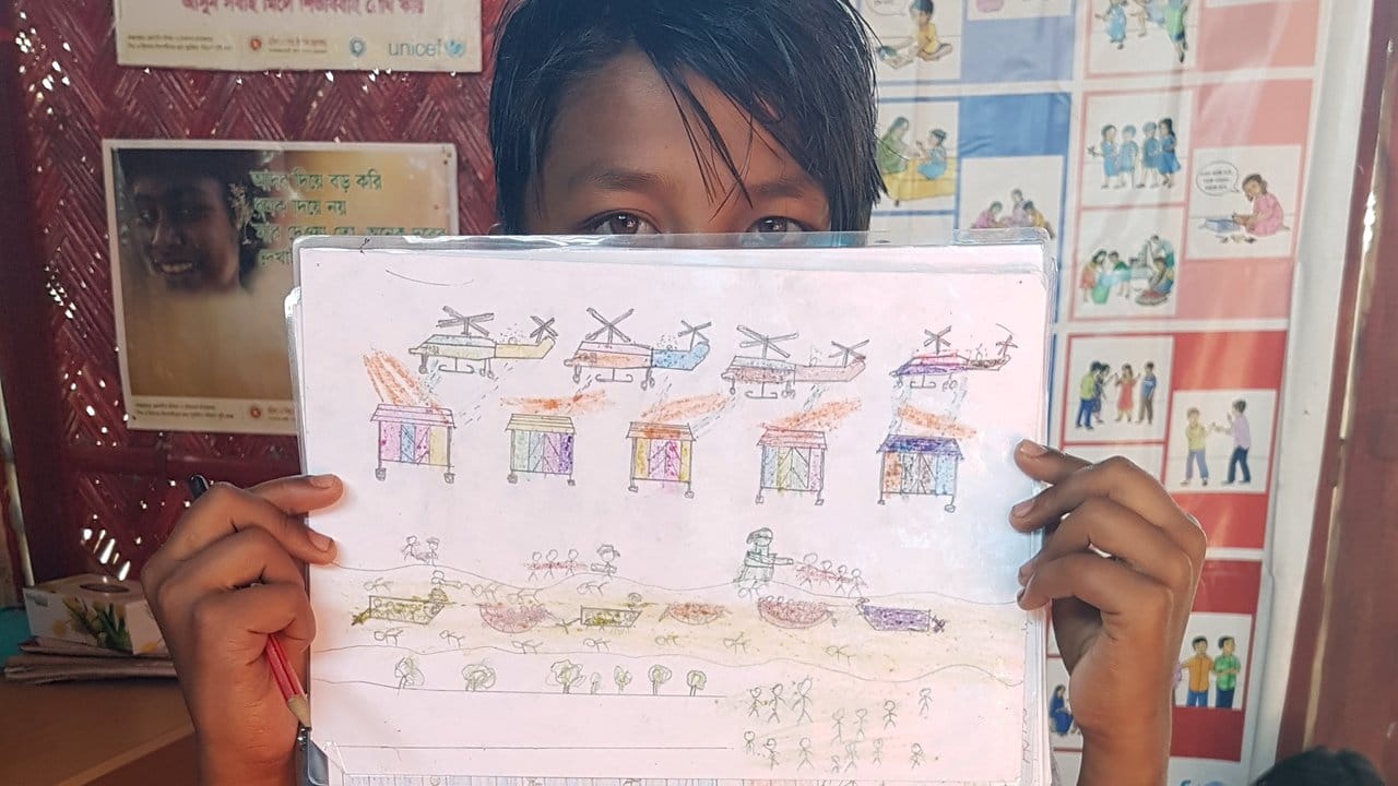 Diese Gewalt hat er in seiner Heimat Myanmar erlebt und im Flüchtlingscamp gezeichnet: Ein elfjähriger Rohingya-Junge mit seinem Bild von Hubschraubern, schießenden Soldaten und brennenden Hütten. Diese Gewalt hat er in seiner Heimat Myanmar erlebt und im Flüchtlingscamp gezeichnet: Ein elfjähriger Rohingya-Junge mit seinem Bild von Hubschraubern, schießenden Soldaten und brennenden Hütten.